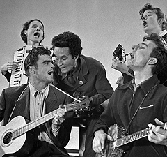 Guthrie (center) performing with fellow Almanac Singers (l-r) Sis Cunningham, Cisco Houston, Pete Seeger and Bess Lomax, 1941
