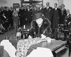 Early in her tenure as Labor secretary, Frances Perkins stitches the NRA “Blue Eagle” label into a dress during a ceremony marking the implementation of several factory-work reforms.