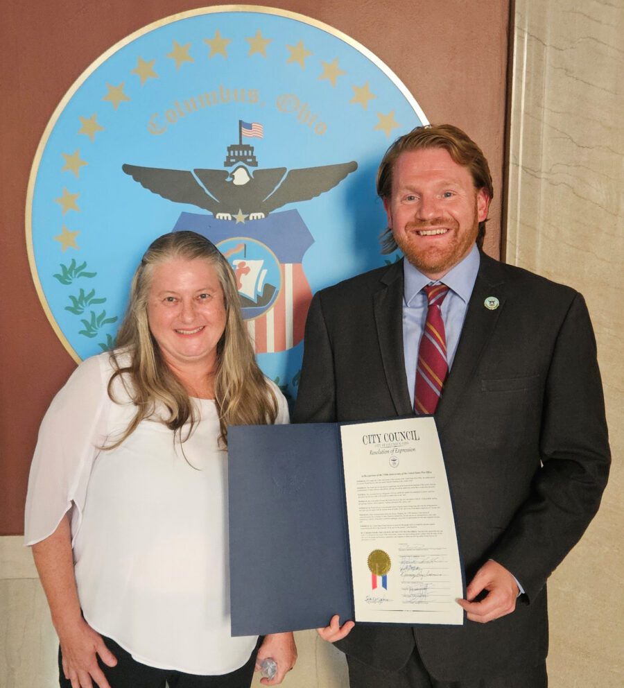 A photo of Columbus Auxiliary Treasurer Angela Lyshe with President Pro Tempore Rob Dorans of the Columbus City Council holding up the signed proclamation